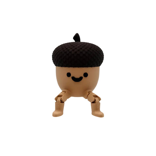 A small acorn-shaped figurine with a smiling face, seated on a clear acrylic block against a plain light gray studio background.