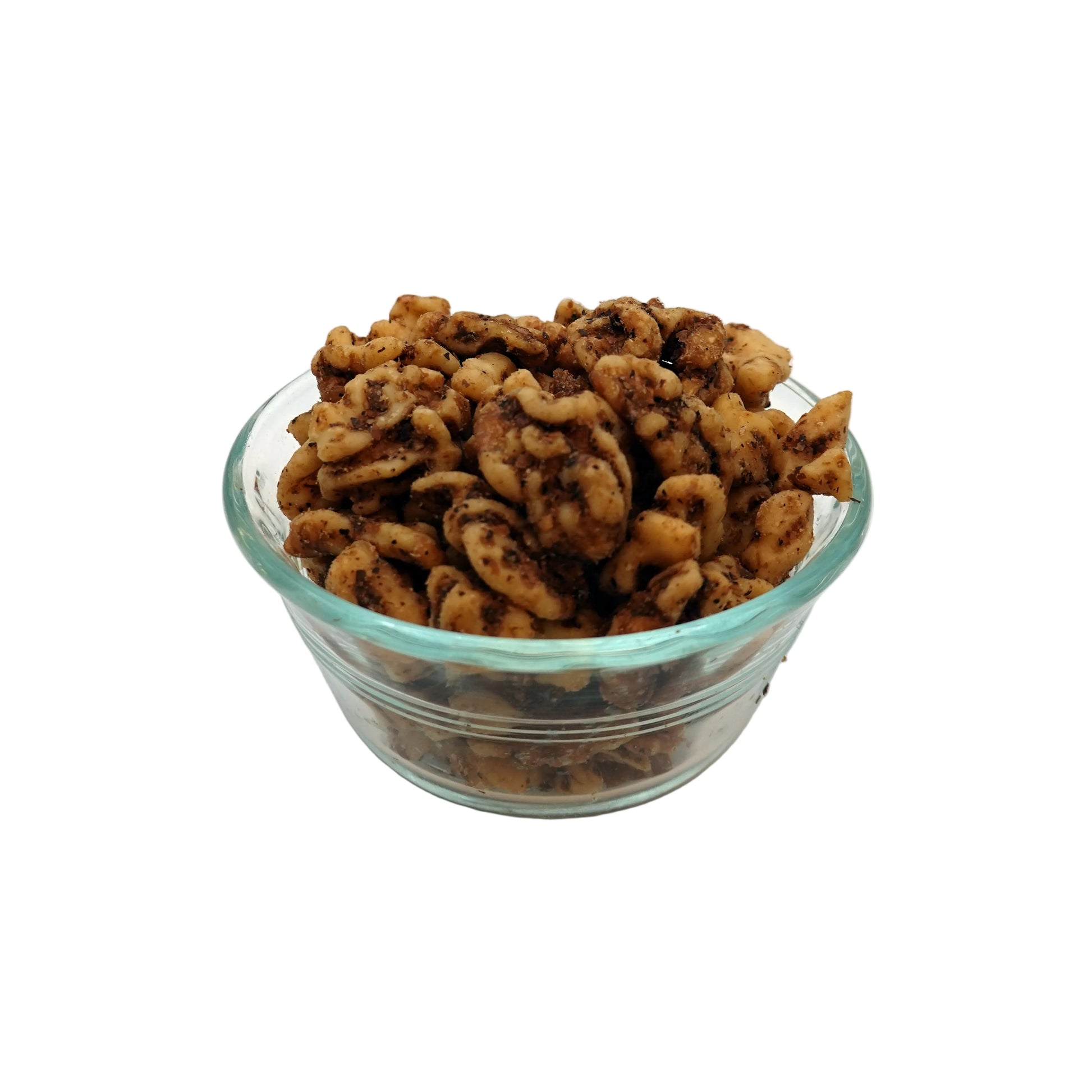 Salted walnuts piled in a small clear glass bowl on a white studio background.