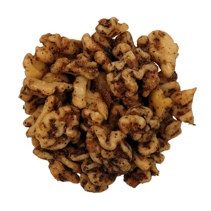 A top-down view of salted walnuts in a clear glass bowl on a plain white background.