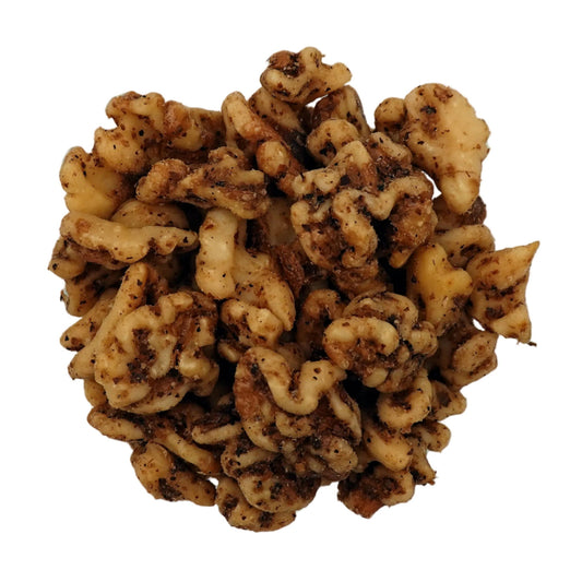A top-down view of unsalted walnuts in a clear glass bowl on a plain white background.