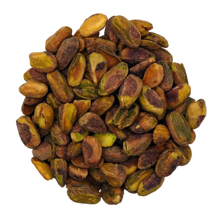 A clear glass bowl filled with roasted salted pistachios, photographed from above on a plain white background.