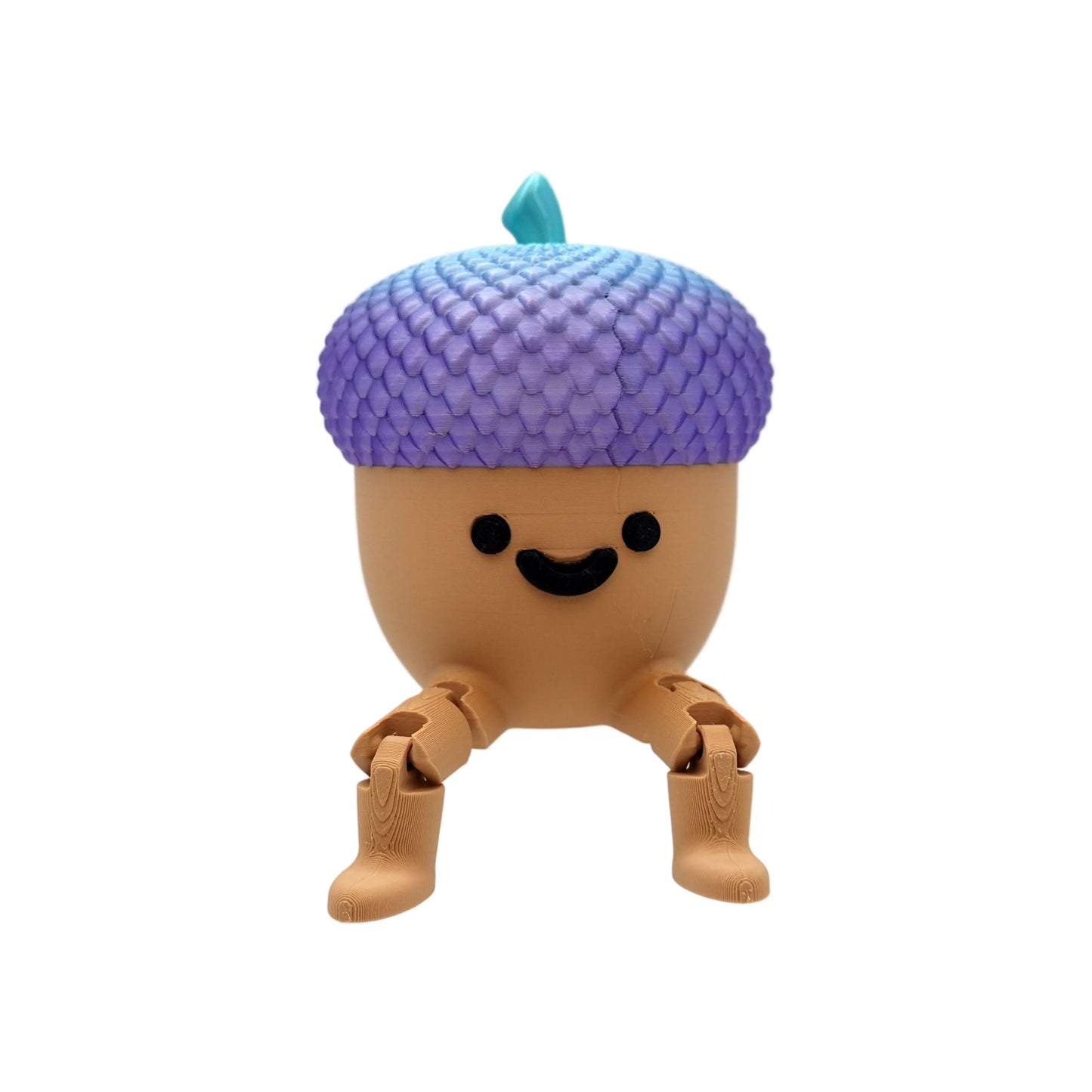 A cute, stylized acorn-shaped toy figure with a purple-to-blue gradient scaly cap, a small teal leaf, and a smiling face, sitting on a clear acrylic display block against a white studio background.