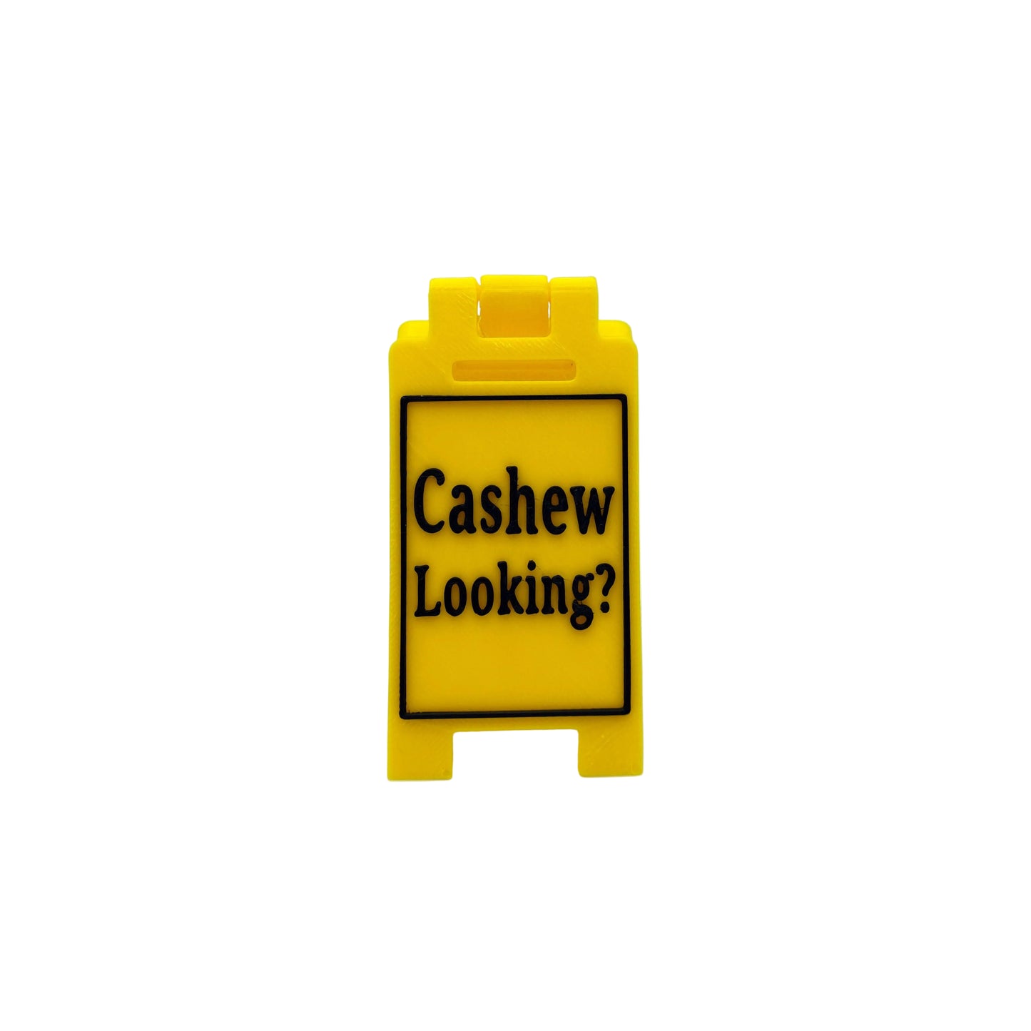 A small yellow plastic sign with black text reading 'Cashew Looking?' on a light gray background.