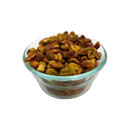 A clear glass bowl filled with unsalted pistachios on a clean white background.
