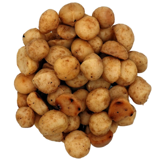 A top-down view of roasted salted macadamias in a clear glass bowl on a white background.