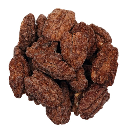 A top-down view of cinnamon glazed pecans piled in a clear glass bowl on a white background.