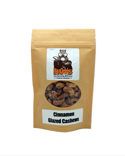 A stand-up kraft paper pouch of 'UR Nuts' Cinnamon Glazed Cashews, featuring a clear window showing the cashews inside and a white label with the brand logo.