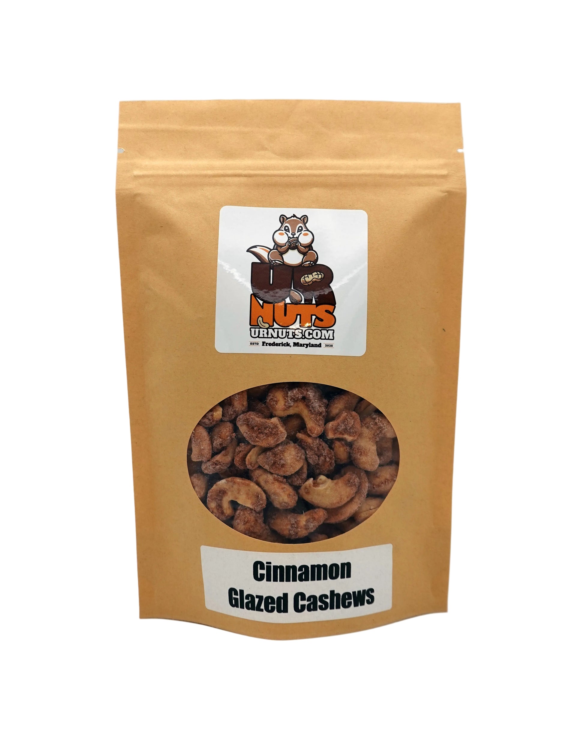 A stand-up kraft paper pouch of 'Cinnamon Glazed Cashews' by UR Nuts, featuring a circular clear window showing the cashews inside and a cartoon raccoon logo on the front.