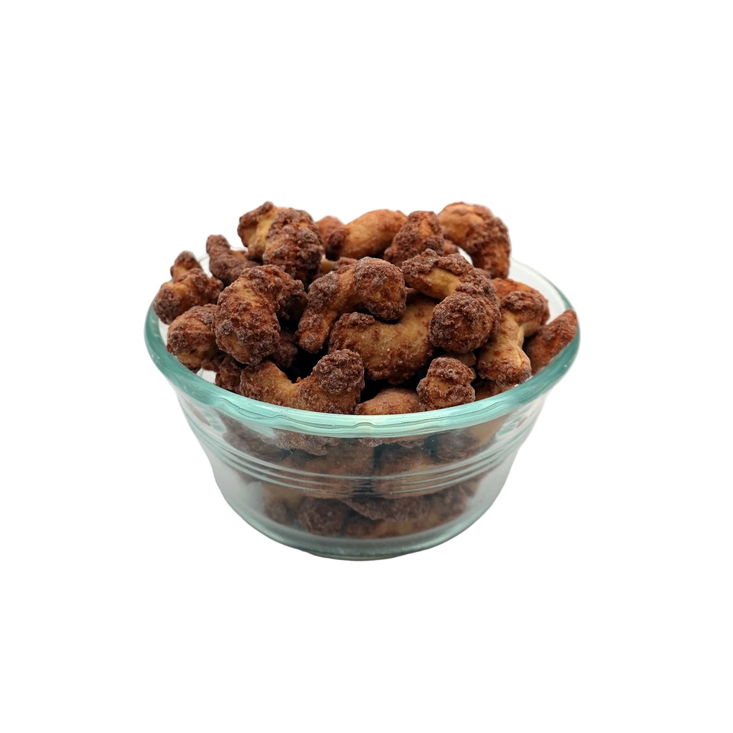cinnamon glazed cashews in a clear glass bowl, set against a seamless light gray studio background.