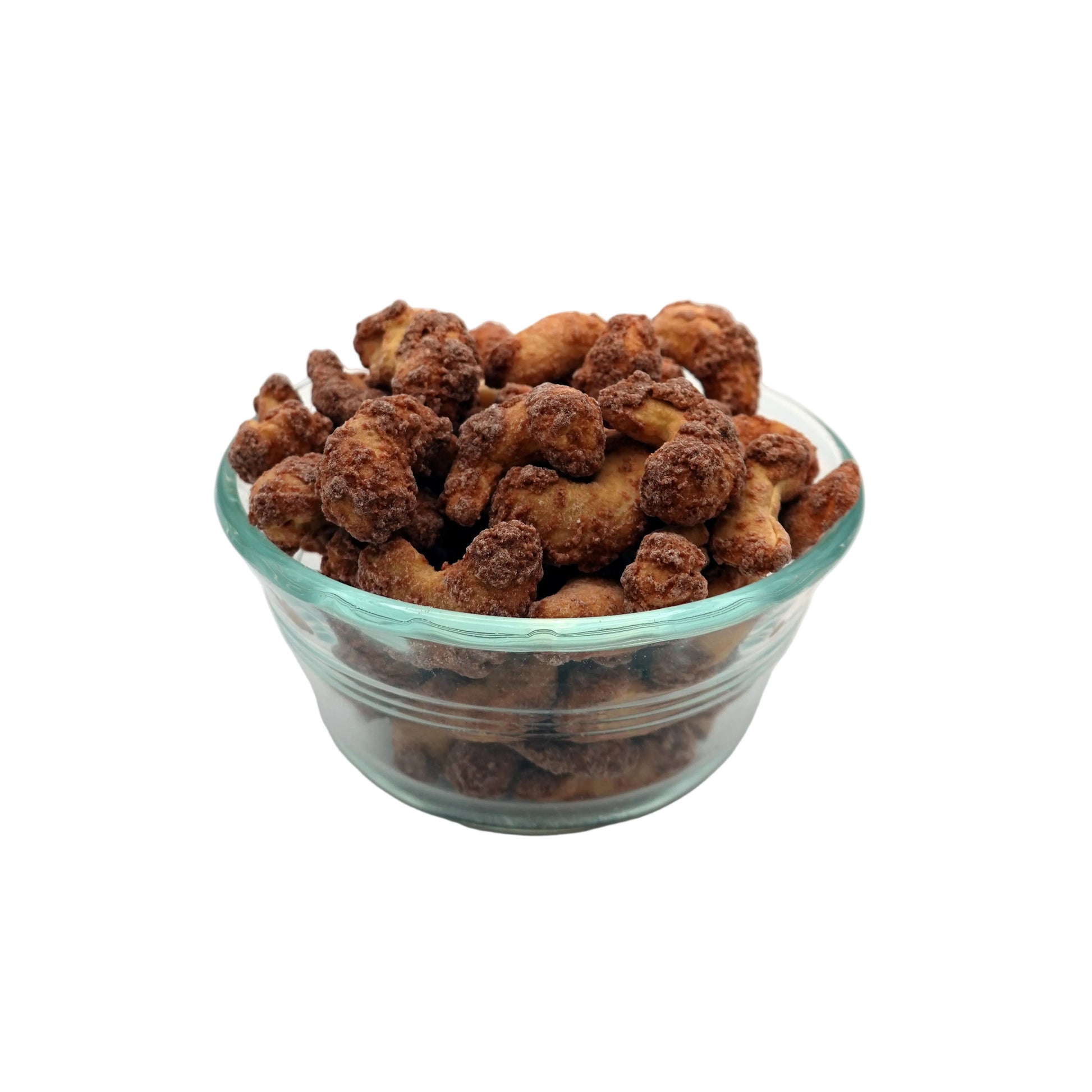 cinnamon glazed cashews in a clear glass bowl, set against a seamless light gray studio background.