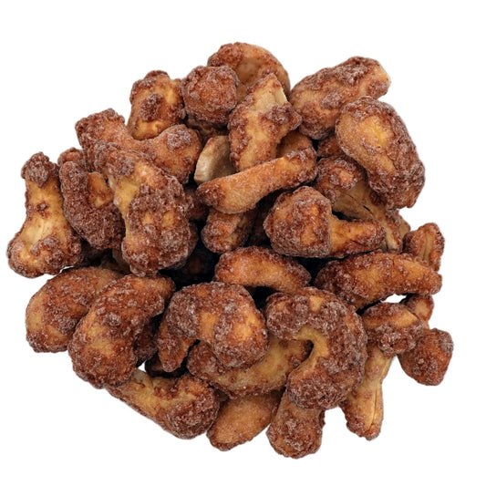 Cinnamon glazed cashews piled in a clear glass bowl, photographed from directly above on a clean white background.