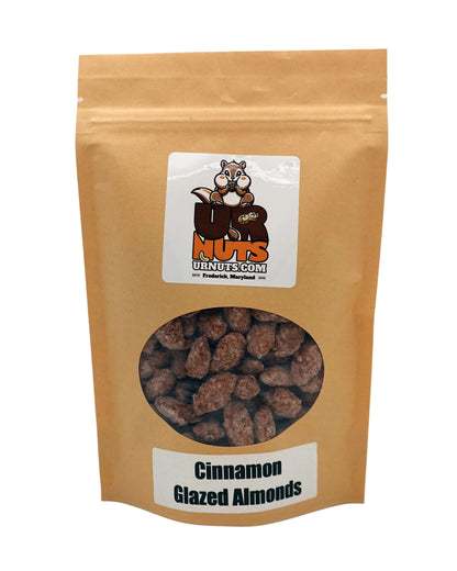 A stand-up kraft paper pouch of UR Nuts Cinnamon Glazed Almonds, featuring a clear circular window showing the almonds inside and a white label with the brand logo.