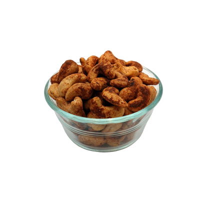A clear glass bowl filled with Spicy Habanero Cashews on a plain white studio background.