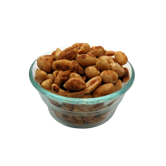 Roasted savory cajun peanuts in a small clear glass bowl, set against a seamless light gray studio background.