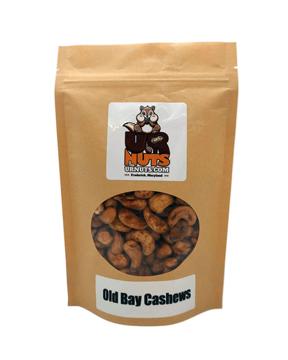 A stand-up kraft paper pouch of Old Bay Cashews from UR Nuts, featuring a clear window showing the cashews inside and a white label with the brand logo.