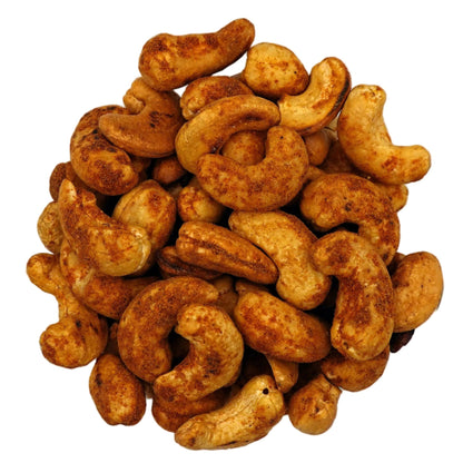 A top-down view of roasted old bay cashews in a clear glass bowl, centered on a plain white background.